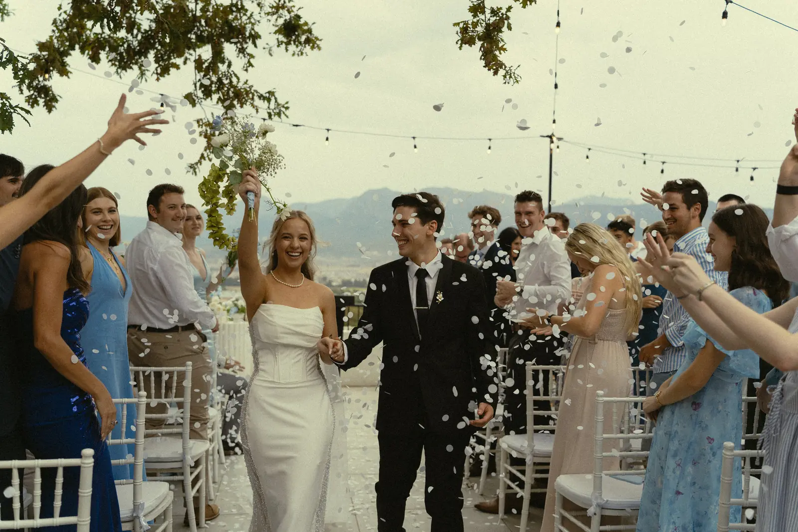 Guests throwing confetti over a bride and groom as they walk out together