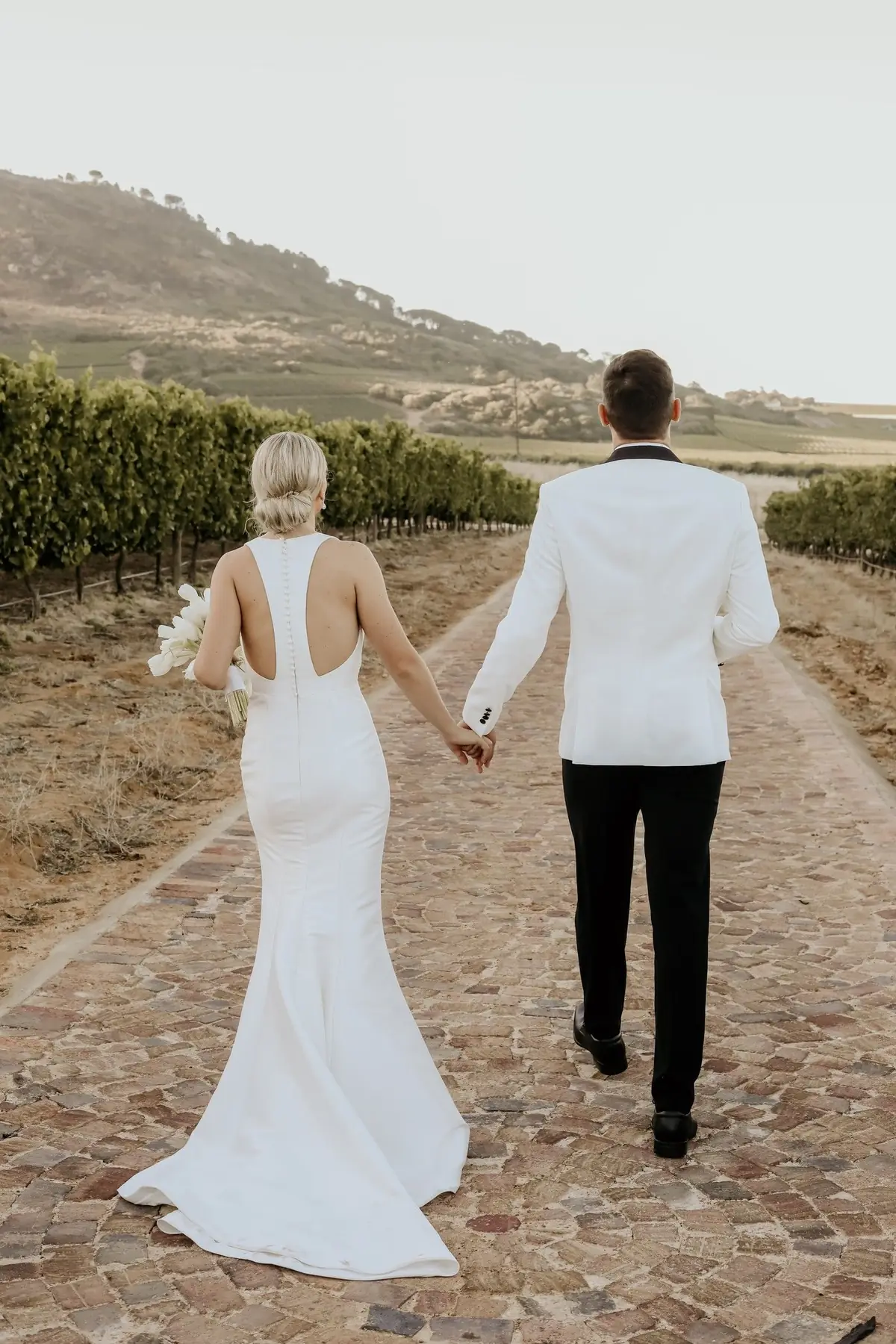 A couple walking down a farm road between the vines