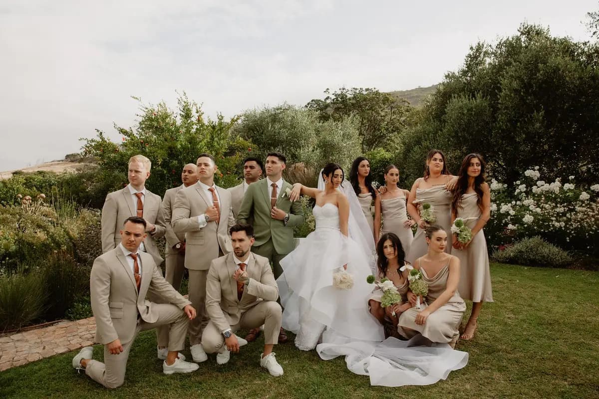 A bride and groom with their bridesmaids and groomsmen on the lawn by the garden